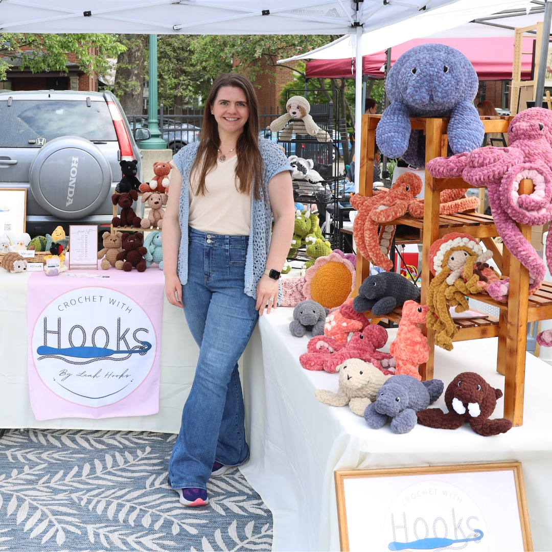 Leah Hooks with handmade crochet plushies at a market booth